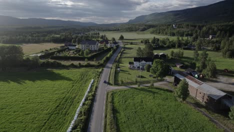 Aerial-View-Of-Car-Driving-Through-A-Road-In-The-Middle-Of-Green-Valley,-Rendalen,-Norway
