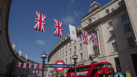 Doppeldeckerbus-An-Der-Kreuzung-Piccadilly-Circus-Road-Mit-Britischen-Flaggen,-Die-über-Der-Regent-Street-In-London,-Großbritannien,-Hängen