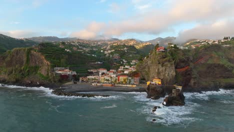 Cinematic-aerial-establishing-view-of-Ponta-do-Sol-Town-Madeira,-Portugal-at-sunset-with-wispy-clouds