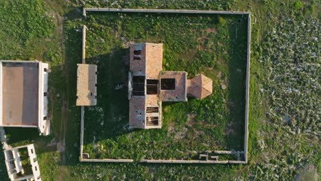 Drone-top-down-rising-above-old-ruined-structure-building-with-brick-walls-in-Sa-Falconera-Madeira