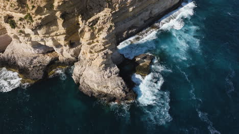 Aerial-view-tilting-around-rocky-cliffs-on-the-coast-of-sunny-Malta-island