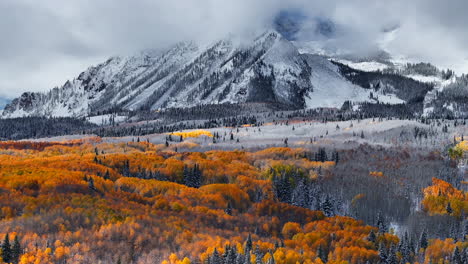 Stunning-Kebler-Pass-Crested-Butte-Colorado-stunning-fall-winter-first-snow-seasons-collide-aerial-cinematic-drone-yellow-aspen-tree-forest-Rocky-Mountains-fog-clouds-lifting-downward-jib-motion