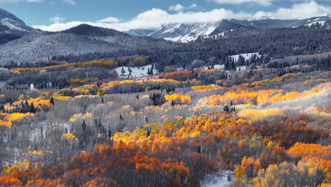 Dramatic-Kebler-Pass-Crested-Butte-Colorado-stunning-fall-winter-first-snow-seasons-collide-aerial-cinematic-drone-yellow-aspen-tree-forest-Rocky-Mountains-fog-clouds-lifting-pan-up-forward-motion