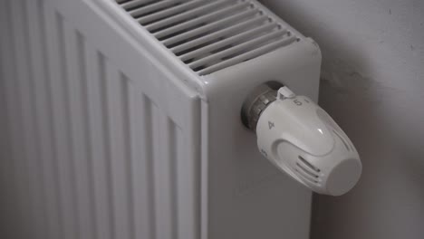 Hand-turning-radiator-or-heating-thermostat-off,-saving-money-during-economics-crisis