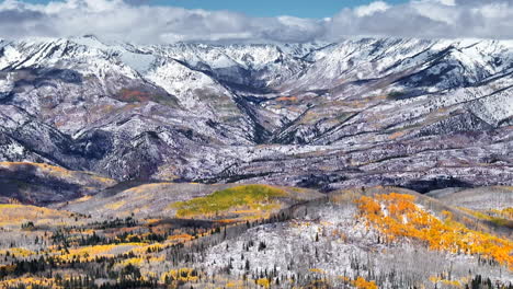 Kebler-Pass-aerial-cinematic-drone-afternoon-Crested-Butte-Gunnison-Colorado-seasons-collide-early-fall-aspen-tree-red-yellow-orange-forest-winter-first-snow-powder-Rocky-Mountain-peak-pan-up-forward