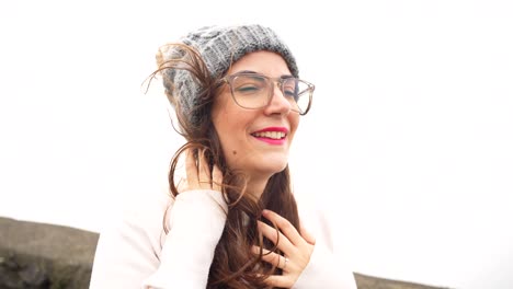 Portrait-of-smiling-woman-with-knitted-beanie-hat-and-hair-in-the-wind