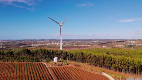 Wind-turbine-next-to-an-old-windmill,-aerial-flying-backwards