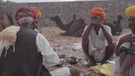 Men-and-animals-relaxing,-Pushkar-Camel-Fair,-Slow-motion,-pan-left