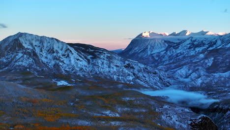 Erstes-Licht-Kebler-Pass-Crested-Butte-Gunnison-Colorado-Jahreszeiten-Absturz-Luftdrohne-Frühherbst-Espenbaum-Rot-Gelb-Orange-Wald-Winter-Erster-Schnee-Kalt-Sonnenaufgang-Wolken-Felsiger-Berggipfel-Rückenbewegung