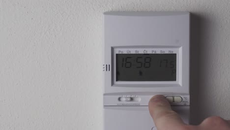 Lowering-heating-thermostat-temperature,-display-and-hand-closeup-view,-reducing-costs