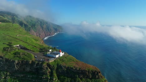 Light-house-on-rocky-ledge-cliff-overlooks-scenic-sweeping-views-with-mystical-clouds