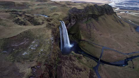 Mystical-waterfall-in-vast-volcanic-landscape-panorama-in-Iceland,-aerial
