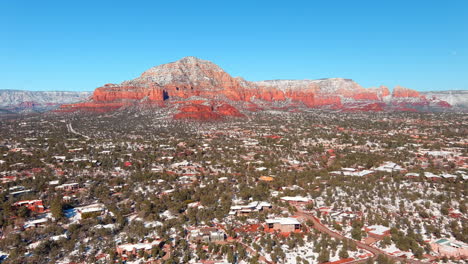 Sedona,-Arizona-and-a-distant-mountain-peak,-Capitol-Butte,-after-light-snow---aerial-parallax