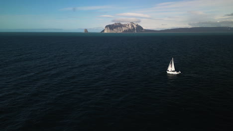 Aerial-tracking-shot-of-a-sailboat-on-the-Gulf-of-Alaska-with-Kayak-island-in-the-background