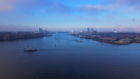 Aerial-Panoramic-Urban-View-over-North-Sea-Canal-with-some-Ships-in-Amsterdam-City,-Twilight