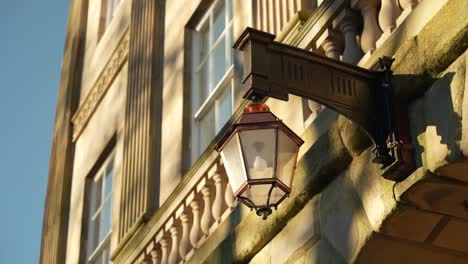 Close-up-of-old-fashioned-brass-lamp-on-Buxton-Crescent-building,-English-Heritage