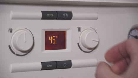 Lowering-water-temperature-radiator-or-heating-on-boiler,-closeup-of-screen-and-hand
