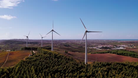 Aerial-view-of-rural-Torres-Vedras,-Portugal,-with-several-wind-turbines-generating-energy,-flying-backwards