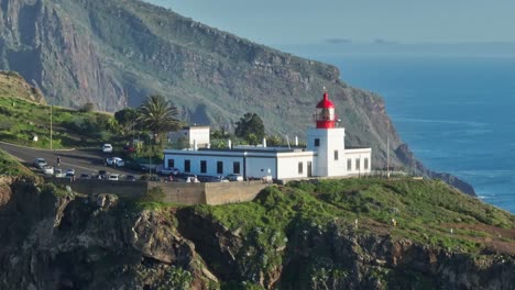 Teleparallaxe-Aus-Der-Luft-Um-Den-Weißen-Und-Roten-Leuchtturm-Auf-Madeira,-Portugal,-Mit-Epischen-Klippen-Dahinter