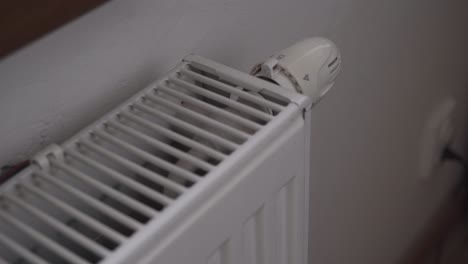 Turning-off-radiator-or-heating,-hand-closeup,-saving-costs,-economic-crisis-concept