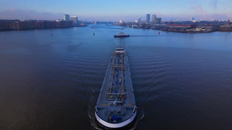 Aerial-Tilt-over-Tanker-Ship-coming-from-the-North-Sea-Canal-in-Amsterdam,-Twilight