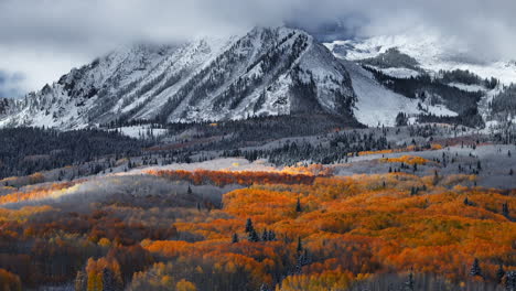 Dramatic-Kebler-Pass-Crested-Butte-Colorado-stunning-fall-winter-first-snow-seasons-collide-aerial-cinematic-drone-yellow-aspen-tree-forest-Rocky-Mountains-fog-clouds-lifting-circle-right-motion