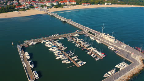 Luftaufnahme-Einer-Drohne,-Die-über-Dem-Yachthafen-Fliegt,-Mit-Festgemachten-Luxusyachten-Und-Der-Stadt-Sopot-Im-Hintergrund