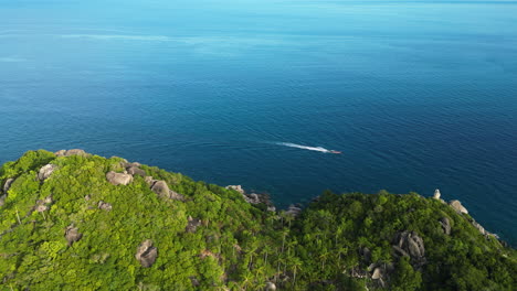 Aerial-view-of-cruising-Tourist-boat-on-ocean-along-green-cliffy-coast-of-koh-tao,-Thailand