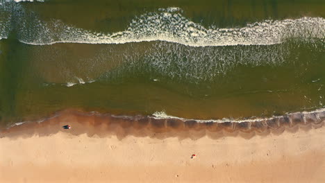 Top-view-of-sea-waves-coming-to-the-beach-at-the-sunset