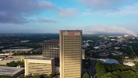 Ascending-drone-shot-showing-Coca-Cola-Headquarter-Building-lighting-by-sun-in-Atlanta-City,-America