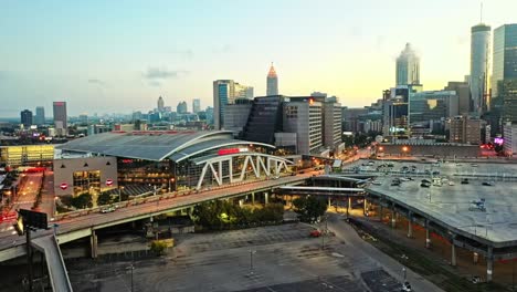 Aerial-approaching-shot-of-State-Farm-Arena-and-skyline-of-Atlanta-City-during-sunset-time,-USA