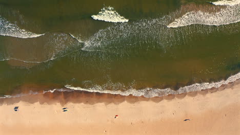 Bird-eye-view-of-drone-flying-above-the-seashore-beach-and-ocean-waves-at-the-sunset
