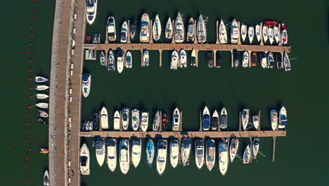 Top-bird-eye-view,-drone-above-the-marina-with-luxurious-yachts-and-motorboats-at-the-sunset