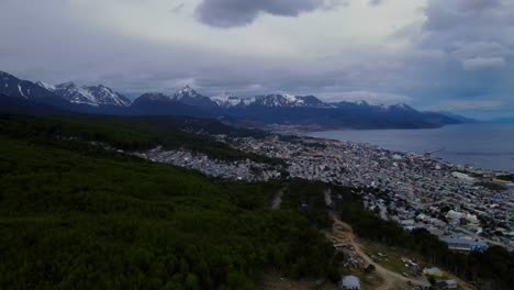 Drone-shot-flying-over-Ushuaia,-Argentina-towards-the-Andes-mountains-in-the-distance-on-a-cloudy-day