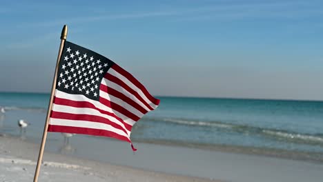 Amerikanische-Flagge-Am-Weißen-Sandstrand-An-Einem-Strahlend-Sonnigen-Tag