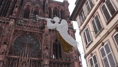 angels-decorations-floating-above-city-street-and-in-front-of-Cathedral-at-Festive-Christmas-market-in-Strasbourg,-France-Europe