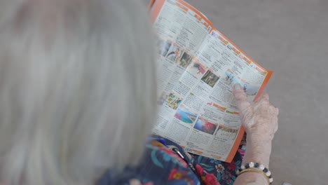 Slow-motion-revealing-shot-of-a-elderly-woman-turning-the-pages-in-a-magazine