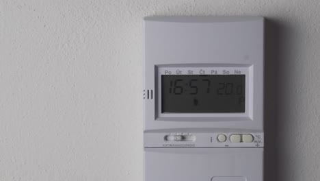 Setting-higher-heating-thermostat-temperature,-digital-display-and-hand-closeup-view