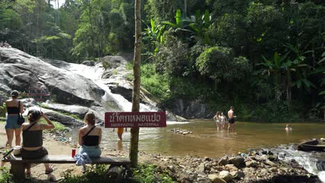 Tourists-enjoying-Mo-Paeng-Waterfall-in-Pai,-Thailand,-with-lush-forest-surroundings-and-clear-water
