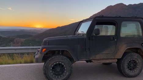 Black-Jeep-4x4-car-and-beautiful-orange-sunset-with-Sierra-Bermeja-view,-fun-ATV-adventures-in-Marbella-Malaga-Spain,-4K-shot