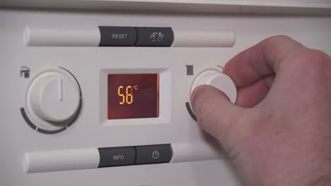 Lowering-heating-water-temperature-on-boiler,-closeup-of-digital-screen-and-hand