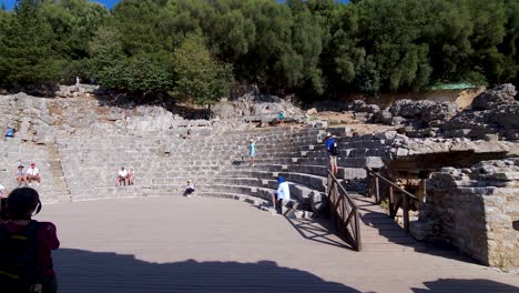 Tourists-Find-Tranquility-on-the-Stone-Seats-of-Butrint's-Amphitheater,-Exploring-the-Ancient-City-on-a-Blissful-Vacation