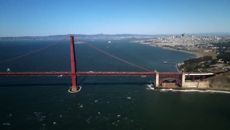 Eine-Filmische-Drohne-Fängt-Die-Golden-Gate-Bridge-In-San-Francisco-In-Zeitlupe-Ein,-Während-Autofahrer-Sie-überqueren-Und-Die-Skyline-Auf-Der-Rechten-Seite-Der-Szene-Sichtbar-Ist