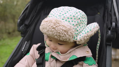 Adorable-Asian-baby-laughs-in-stroller-whilst-wearing-warm-wooly-hat-to-keep-him-warm-during-winter