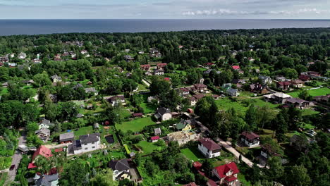 Aerial-footage-of-a-town-with-lot-of-greenery-and-seacoast-visible-in-the-background-nearby