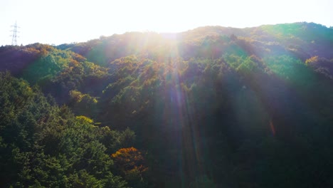 Sun-Peaks-over-Autumn-Forested-Mountain,-Aerial-Tilt-Shot