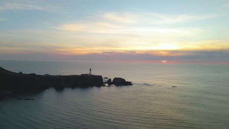 Drone-shot-of-the-Yaquina-Head-Lighthouse-looking-out-over-the-sunset-in-Newport,-Oregon