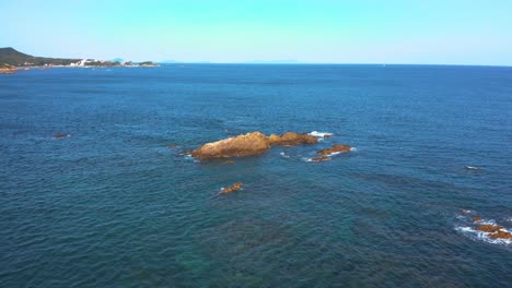 Flying-Over-Seascape,-Towards-Rocky-Reef-on-Sunny-Day