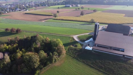 Aerial-view-of-small-farm-house-surrounded-by-fields-in-Switzerland-countryside