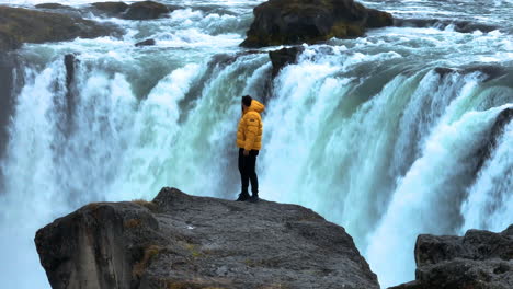 Orbiting-On-A-Man-Standing-Over-Rock-Cliffs-Near-Godafoss-Waterfall-In-Iceland